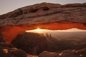 Sunrise above an arch on Mesa Arch trail