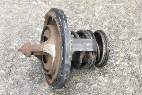 rusty car thermostat on the ground 